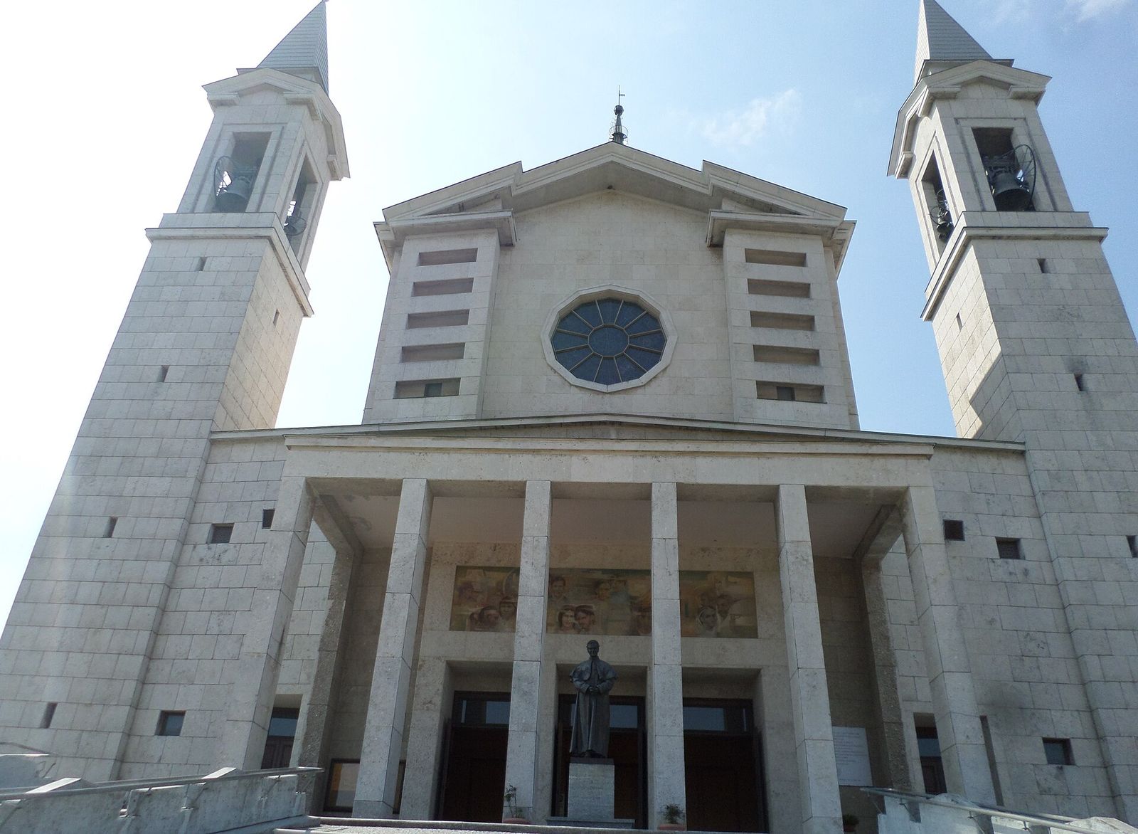 La facciata della basilica di Don Bosco al Colle Don Bosco, con i due campanili e la statua del santo davanti all'ingresso