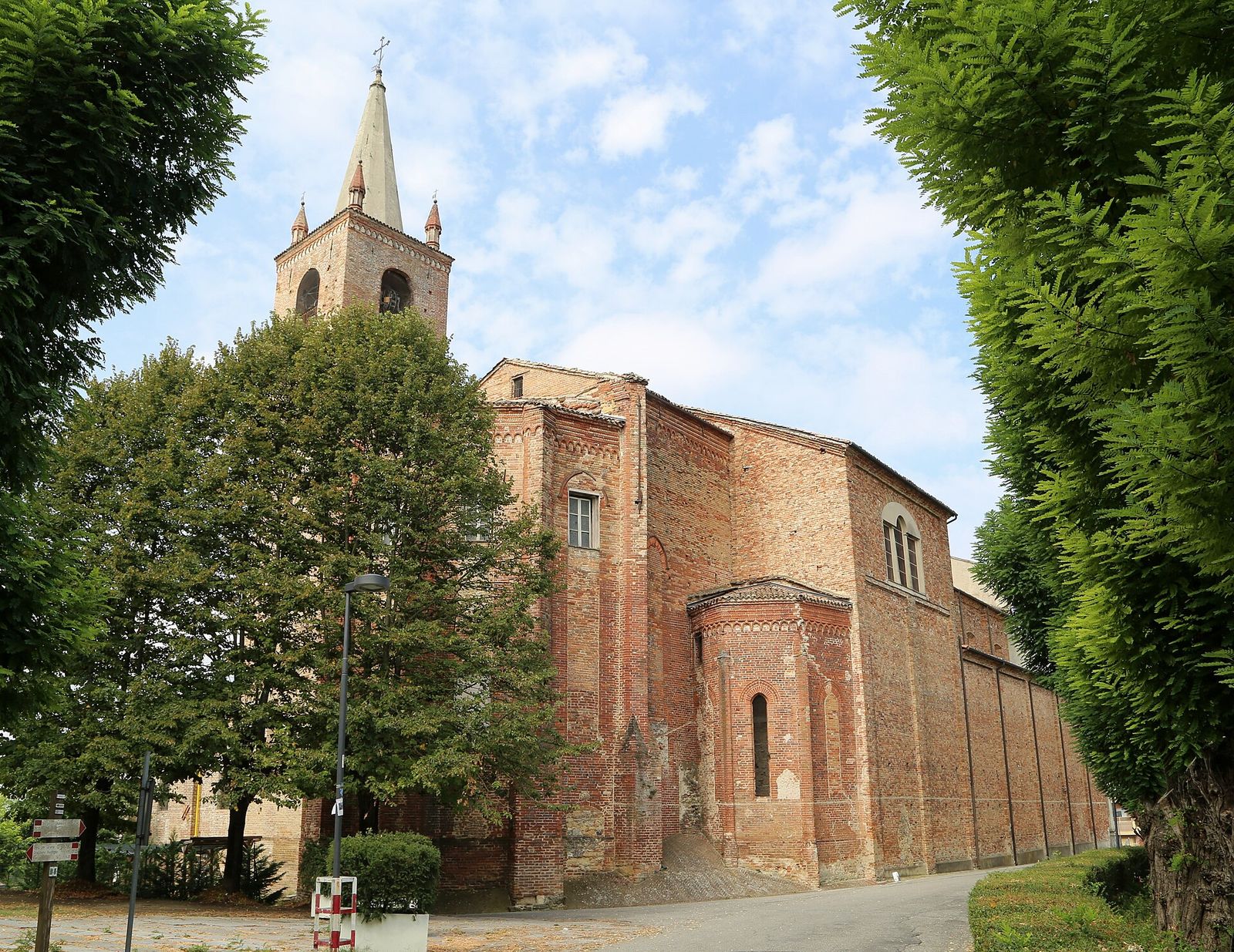 Il fianco in mattoni e il campanile della chiesa di San Francesco a Moncalvo, incorniciati dagli alberi del viale
