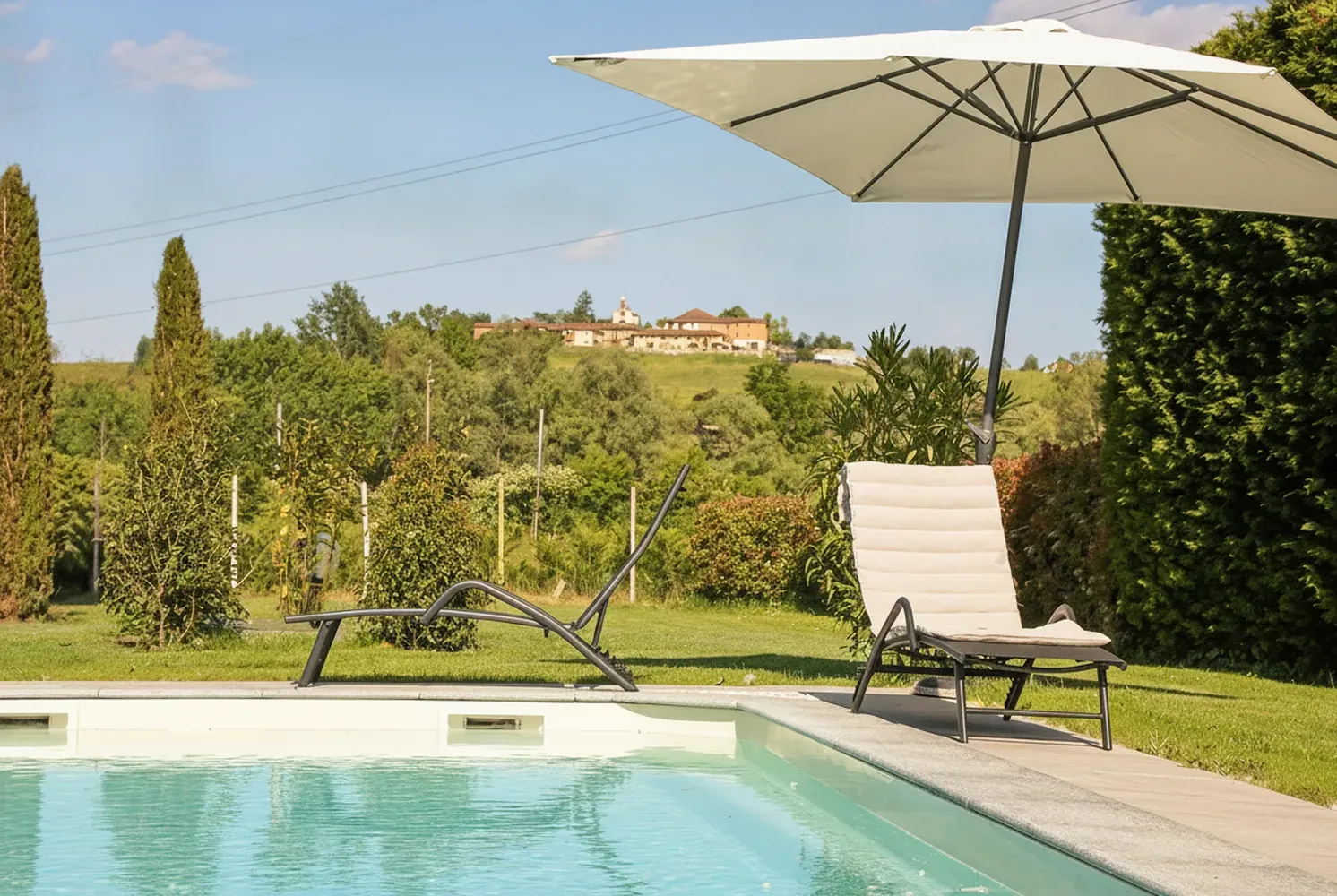 Bordo piscina con sdraio e ombrellone